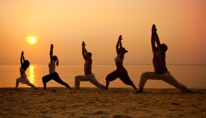 Séance de yoga au lever du soleil sur une plage de l’île Maurice face au lagon.